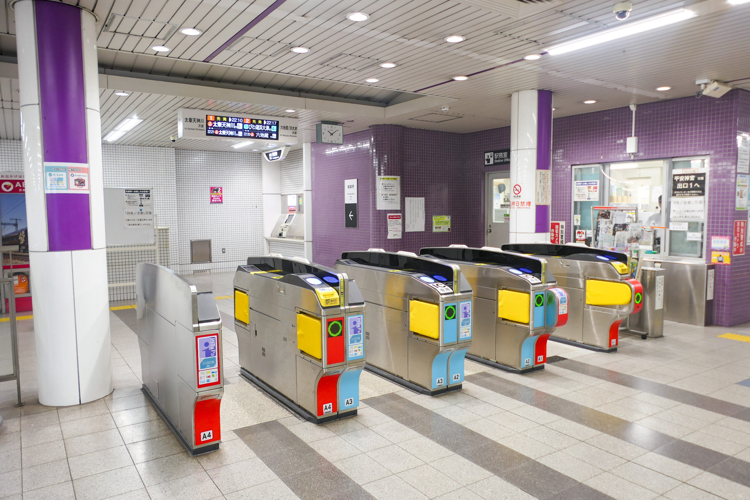Portiques d'accès et guichet de la station de métro Higashiyama, à Kyoto, avec des colonnes violettes.